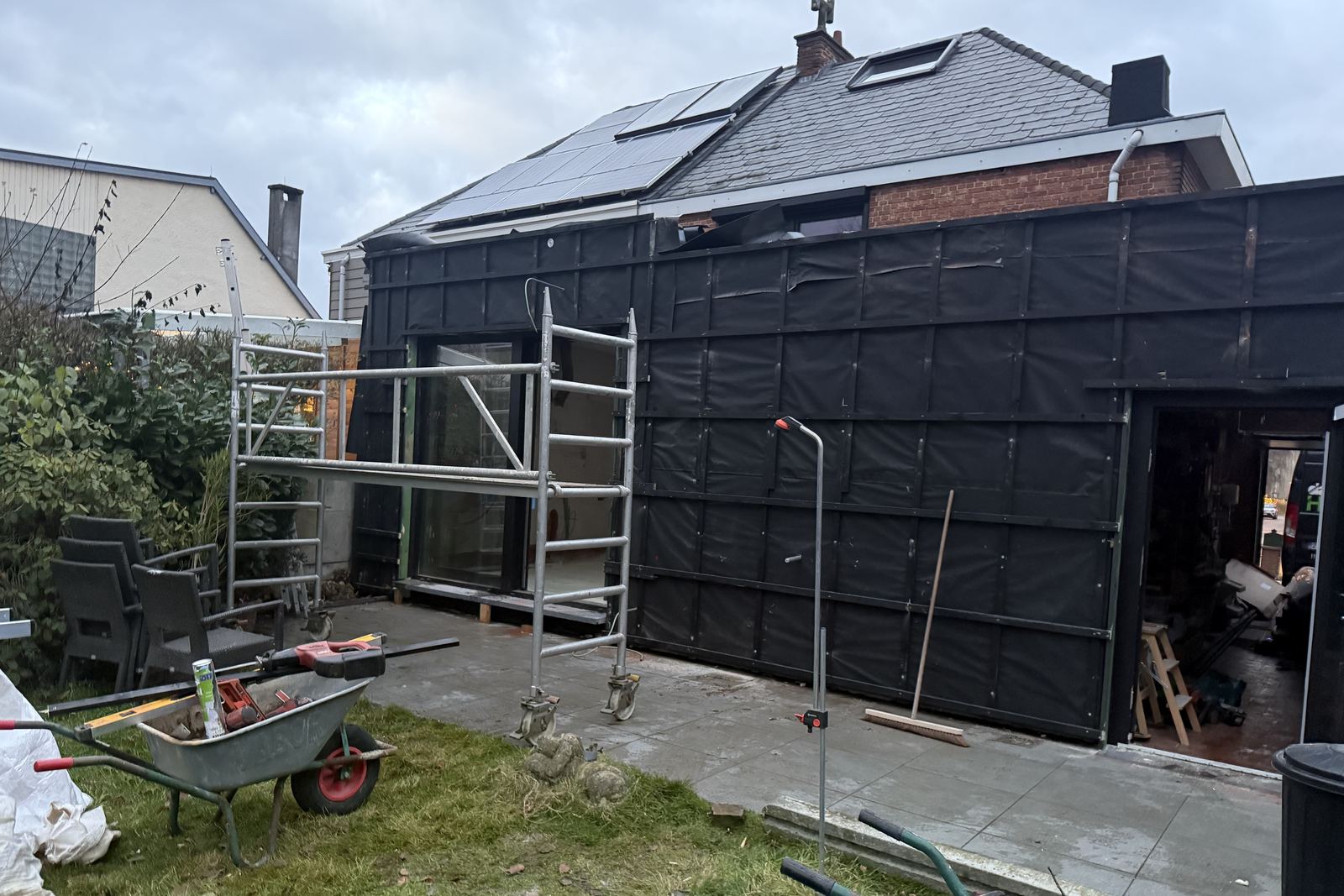 Gevel van een aanbouw met zwart dampscherm en steiger
